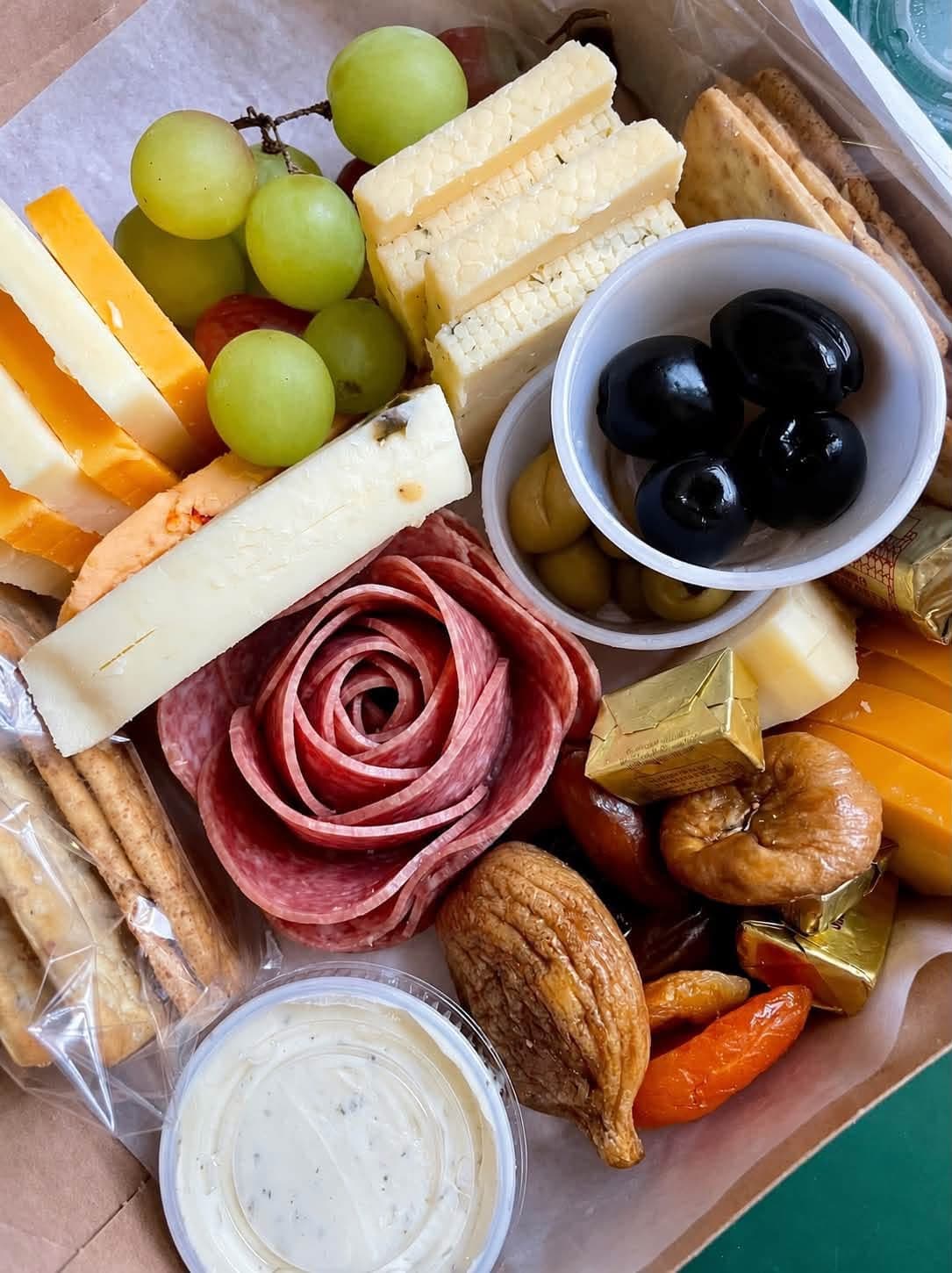 Close view of an Iron Turbine charcuterie box with meats, cheeses, fruit, and olives.