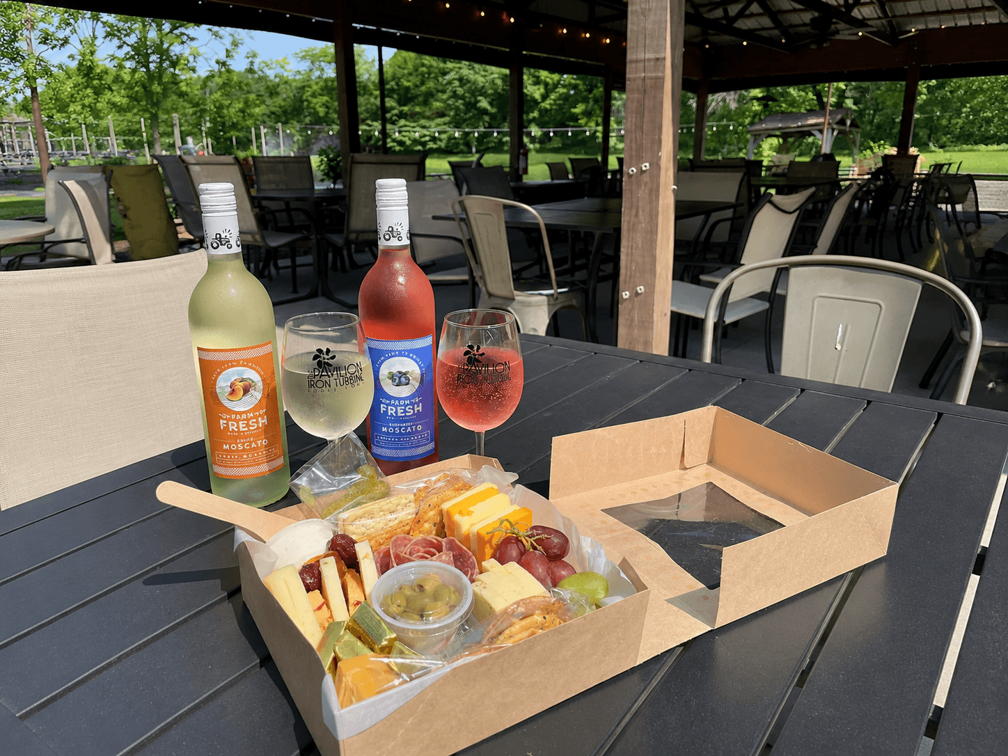 Wine, glasses, and a charcuterie box on an Iron Turbine patio table.