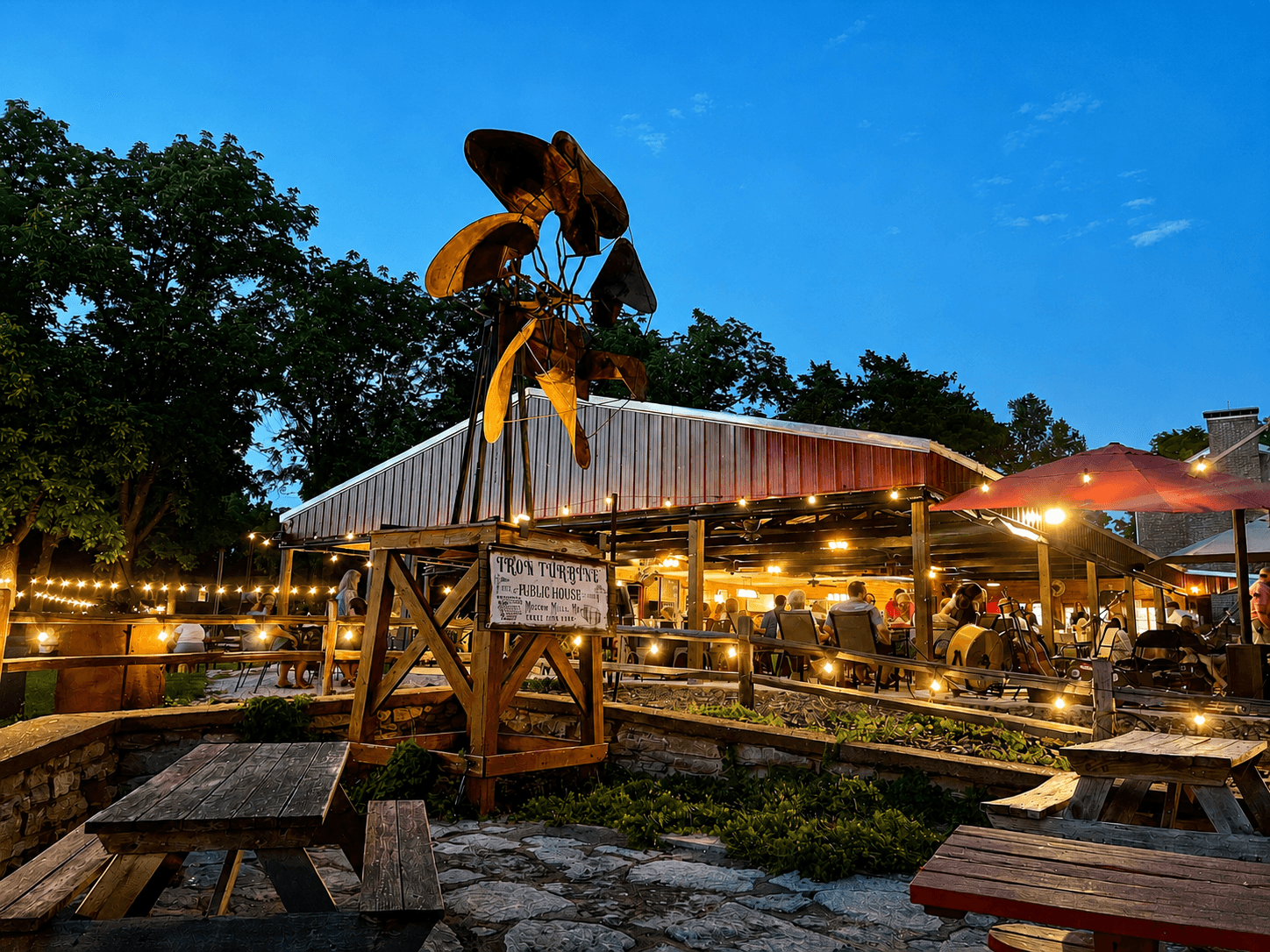 The Iron Turbine patio lit at evening with guests seated under string lights.