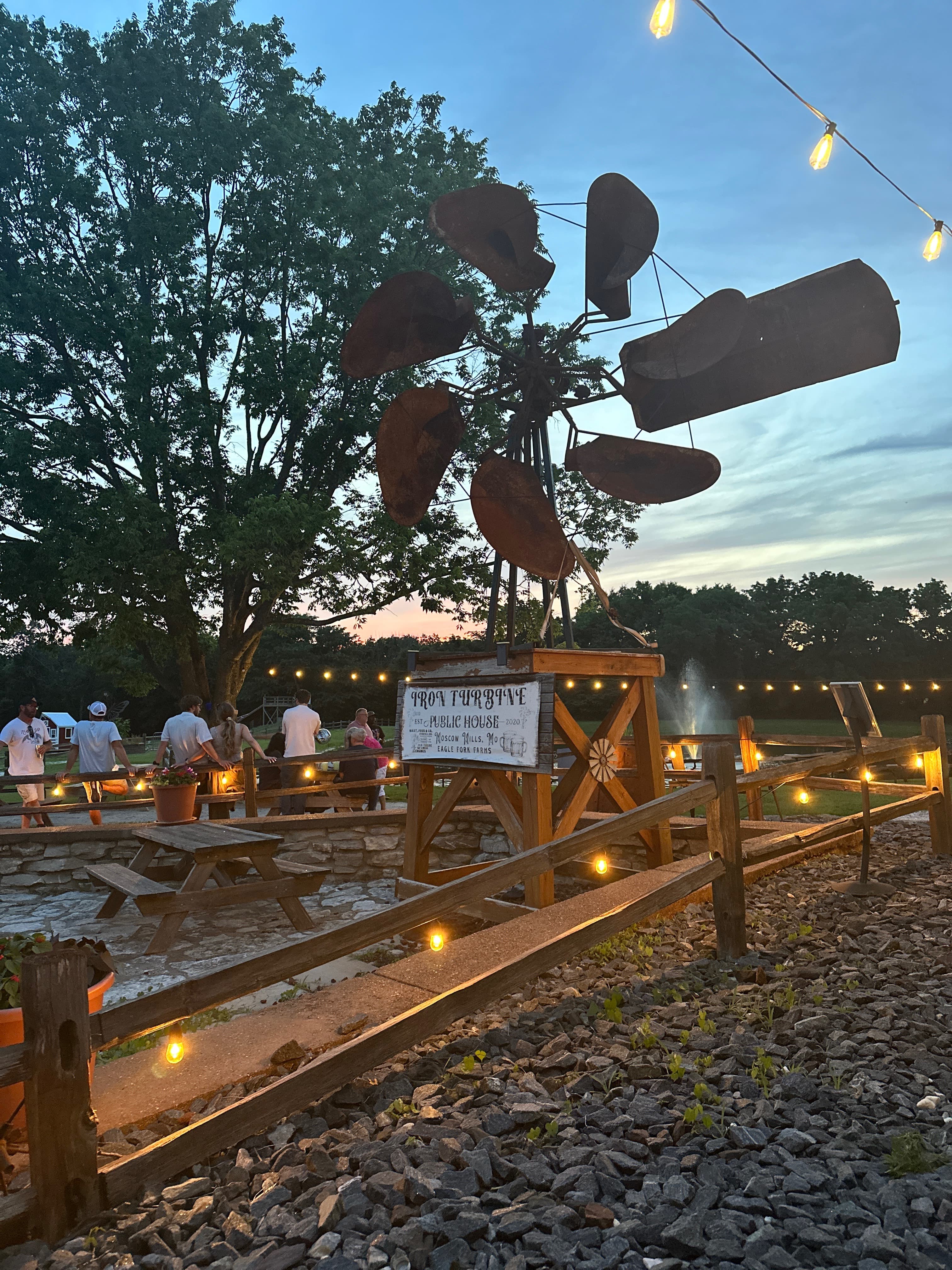The Iron Turbine, patio seating, and string lights glowing at dusk.