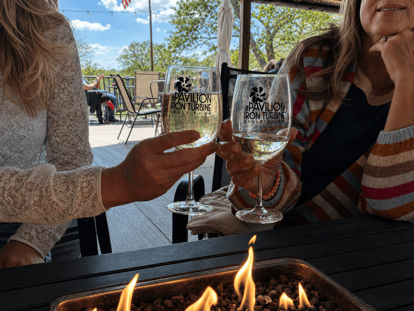 Guests raising Iron Turbine wine glasses beside the patio fire table.