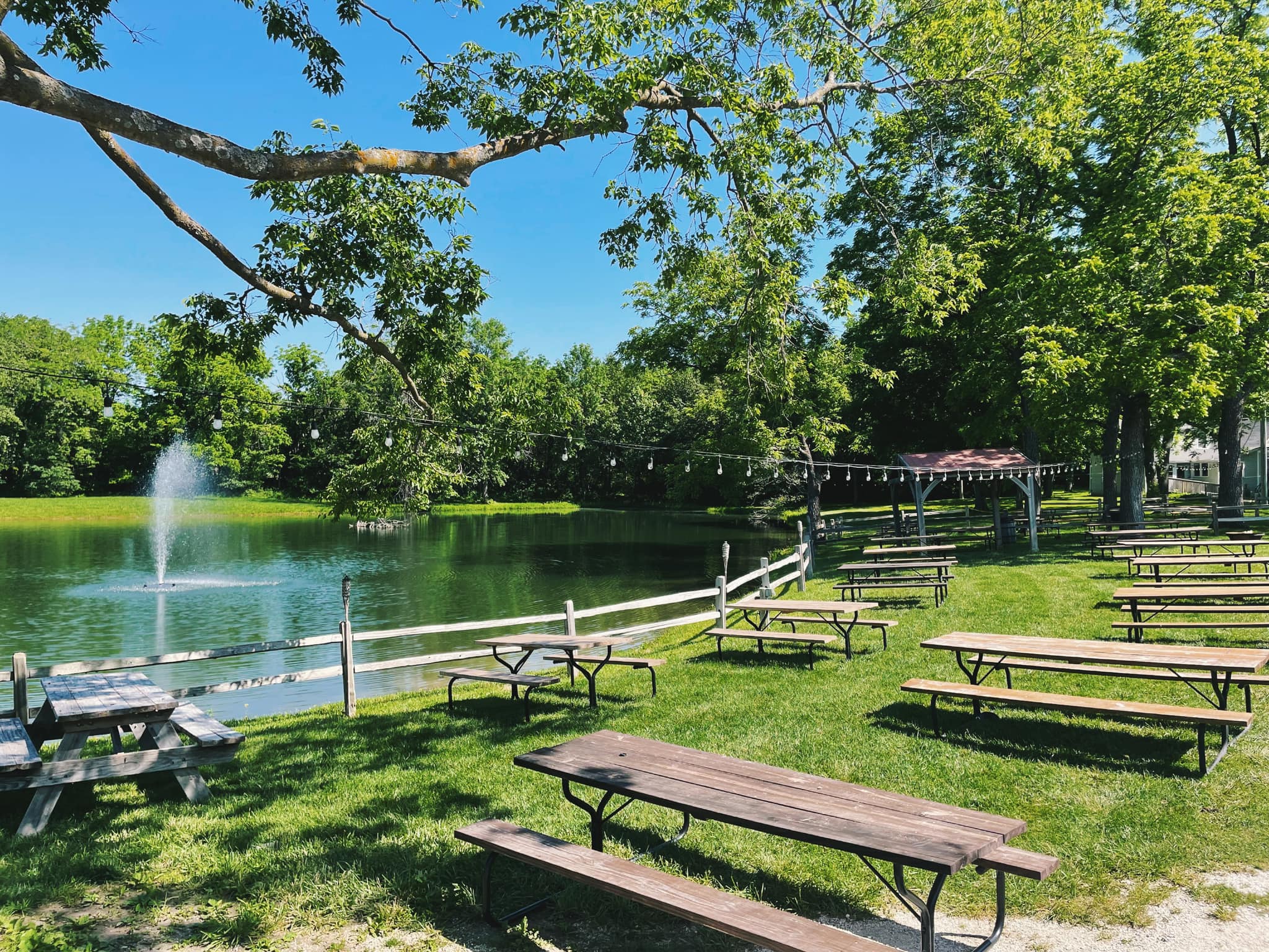 Picnic tables on the lawn beside the pond and fountain at Eagle Fork Farms.